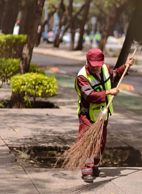 A professional cleaner in a red uniform holding a vacuum near a van, ready for service.